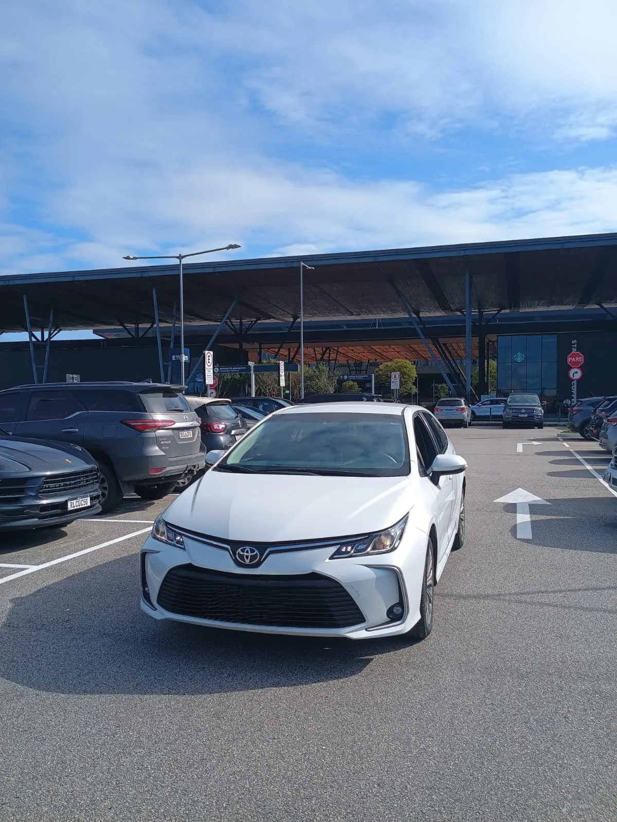 Toyota Corolla branco no estacionamento de um terminal de aeroporto