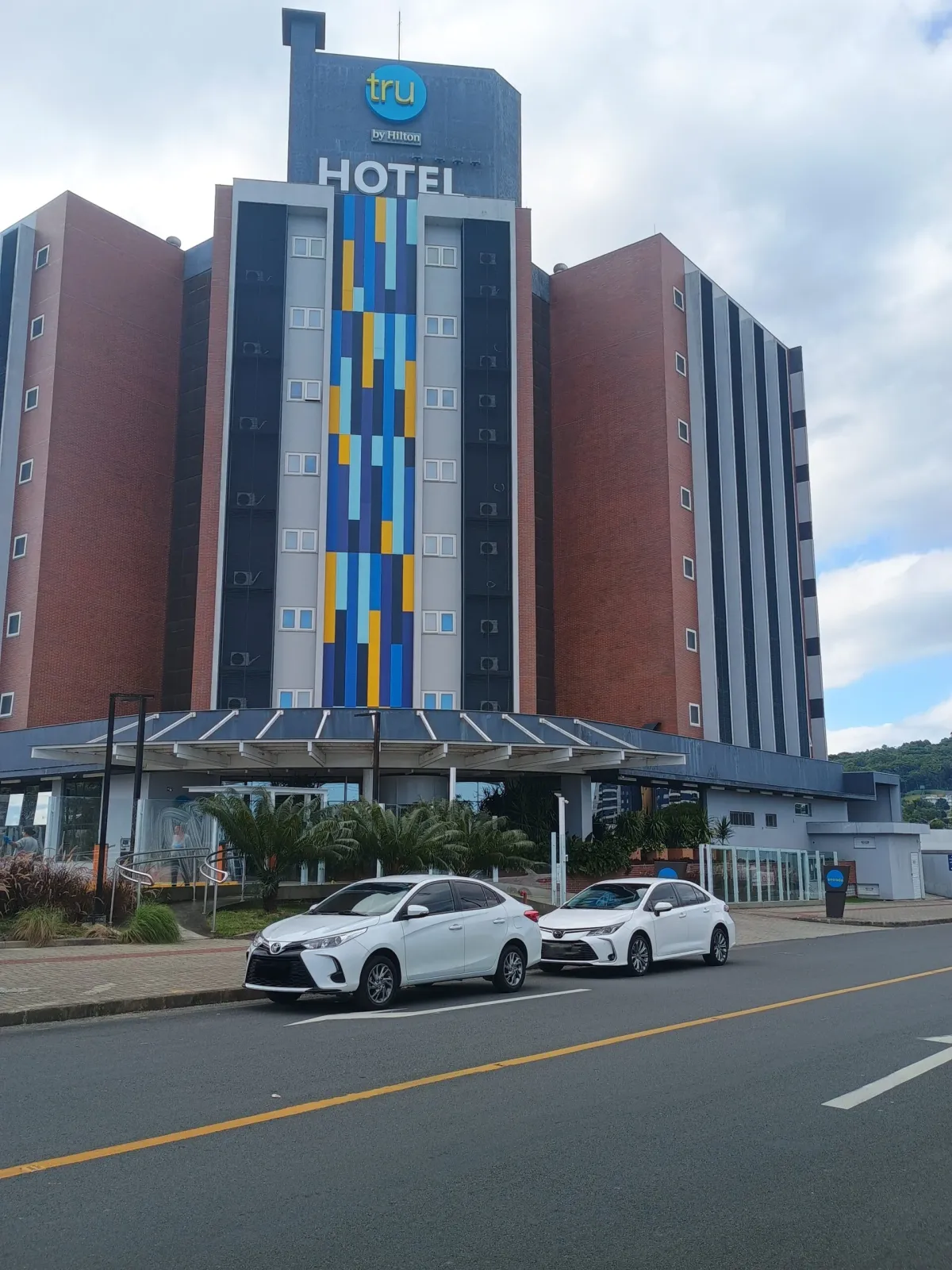 Dois Toyota Corolla brancos estacionados em frente a um hotel